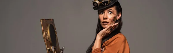 Panoramic shot of surprised steampunk woman using vintage laptop isolated on grey — Stock Photo