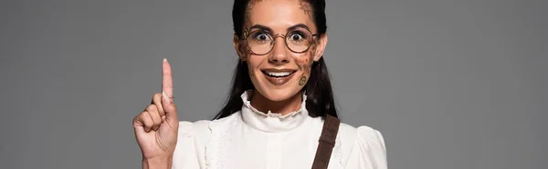 Panoramic shot of excited steampunk woman in glasses showing idea sign isolated on grey — Stock Photo