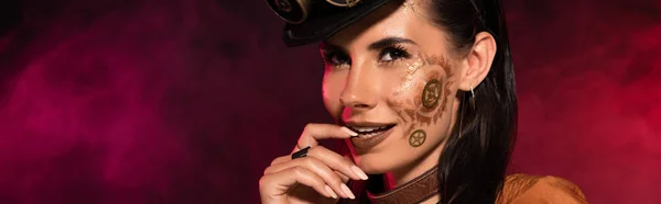Panoramic shot of smiling steampunk woman with makeup in pink smoke — Stock Photo