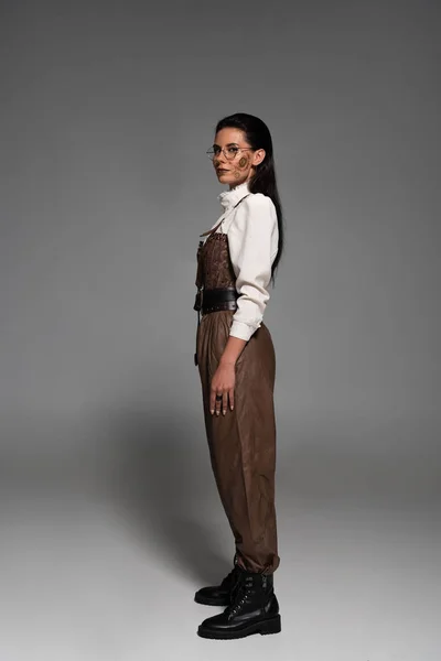 Full length view of attractive steampunk woman in glasses on grey — Stock Photo