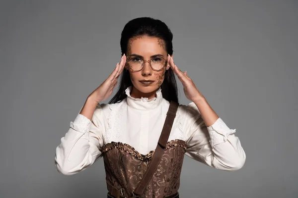 Vue de face de la femme steampunk avec des lunettes de maquillage touchantes isolées sur gris — Photo de stock