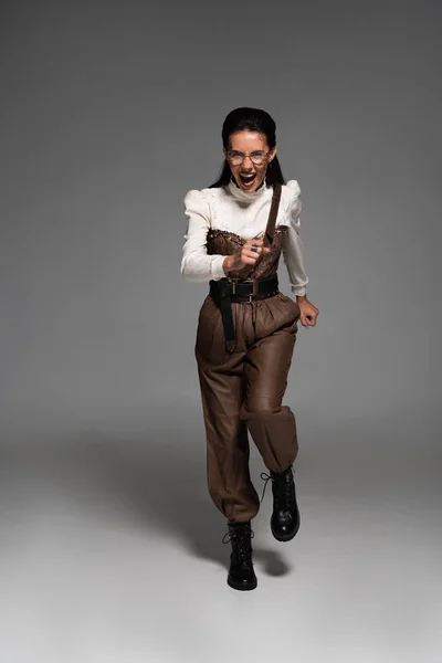 Full length view of screaming steampunk woman running on grey — Stock Photo