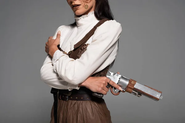 Обрезанный вид женщины с пистолетом в руках на сером фоне — стоковое фото