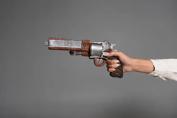 Vue recadrée d'une femme tenant un pistolet vintage isolé sur gris — Photo de stock