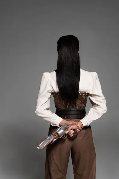 Back view da mulher steampunk segurando pistola vintage em cinza — Fotografia de Stock