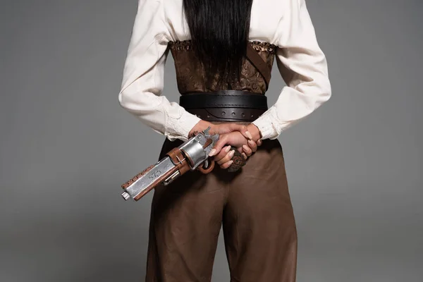 Cropped view of steampunk woman holding vintage pistol on grey — Stock Photo