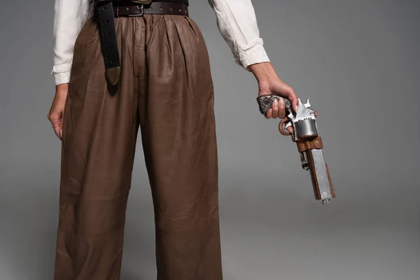 Cropped view of steampunk woman holding vintage pistol on grey — Stock Photo