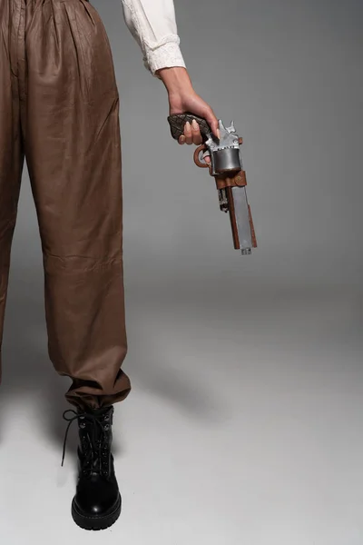 Vue recadrée de la femme steampunk tenant pistolet vintage sur gris — Photo de stock