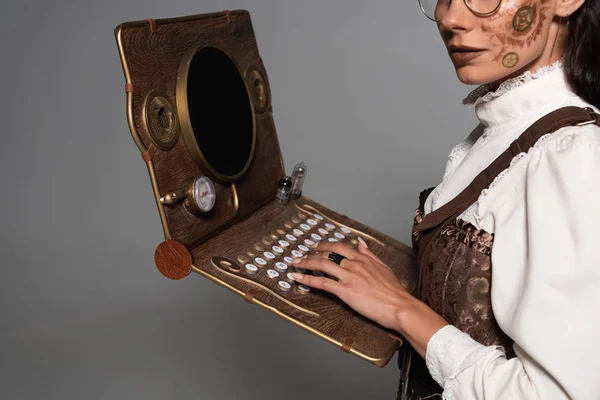 Cropped view of steampunk woman using vintage laptop isolated on grey — Stock Photo