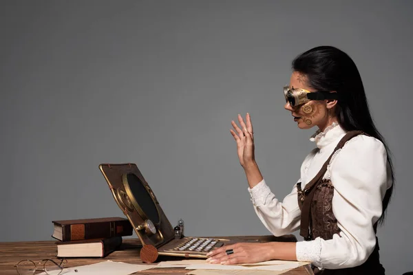 Steampunk donna in occhiali agitando la mano durante la video chat isolato su grigio — Foto stock