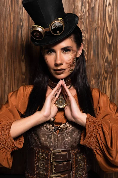 Attraente donna con steampunk trucco toccare medaglione su legno — Foto stock