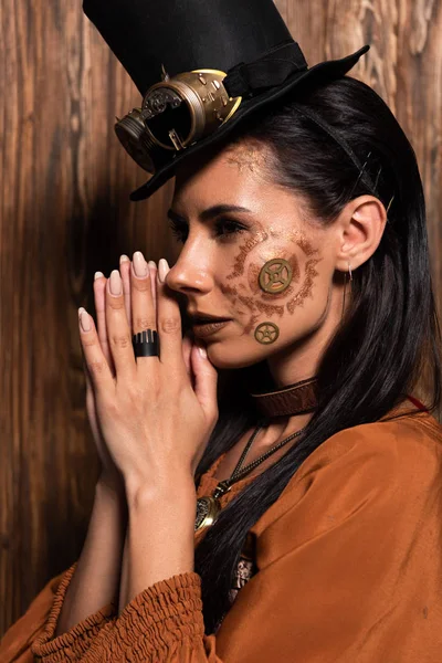 Pensive steampunk woman showing please gesture on wooden — Stock Photo