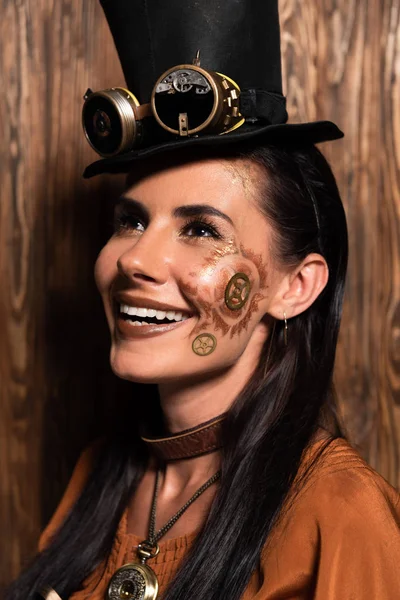 Allegra donna steampunk con trucco alzando lo sguardo e sorridendo su legno — Foto stock