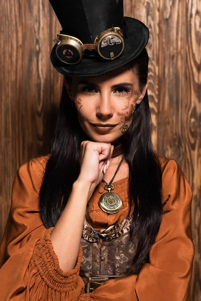 Front view of attractive woman propping chin with fist and looking at camera on wooden — Stock Photo