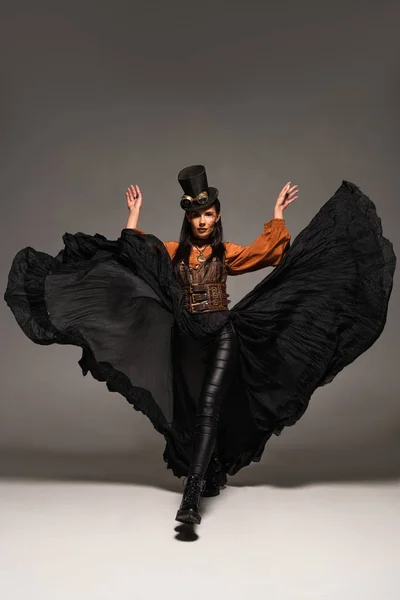 Full length view of attractive steampunk woman in top hat with goggles on grey — Stock Photo