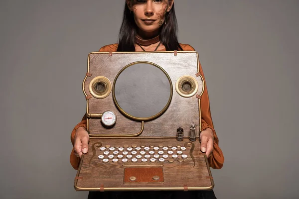 Обрезанный вид женщины, показывающей стимпанк ноутбук изолирован на серый — стоковое фото