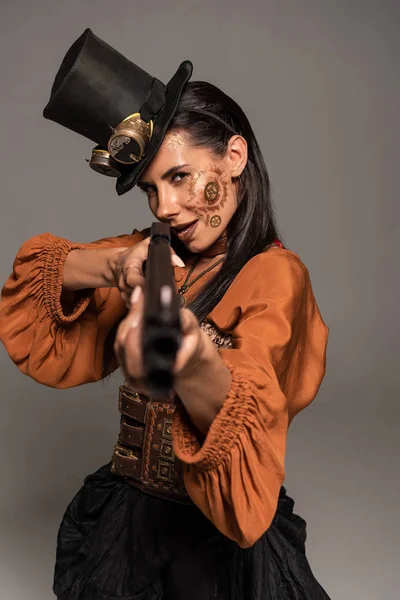 Fokussierte Steampunk-Frau mit Zylinder zielt mit Pistole isoliert auf grau — Stockfoto