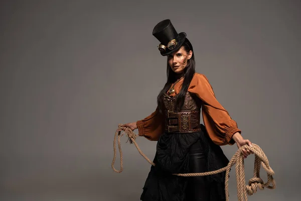 Attractive steampunk girl in top hat holding lasso isolated on grey — Stock Photo