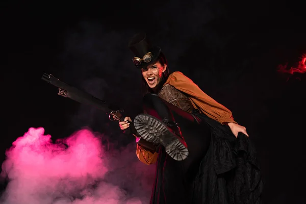 Agressivo steampunk mulher no topo chapéu segurando arma no rosa fumaça no preto — Fotografia de Stock