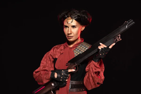 Confident steampunk girl in leather gloves holding gun isolated on black — Stock Photo