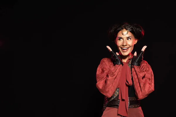 Front view of attractive excited steampunk woman in leather gloves laughing isolated on black — Stock Photo