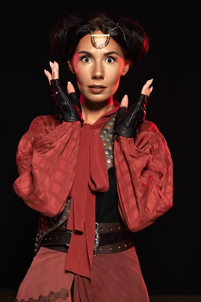 Front view of attractive surprised steampunk woman in leather gloves isolated on black — Stock Photo