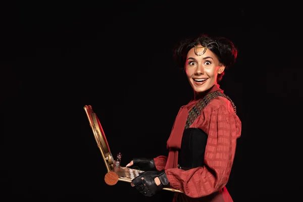 Attractive steampunk woman using laptop and smiling isolated on black — Stock Photo