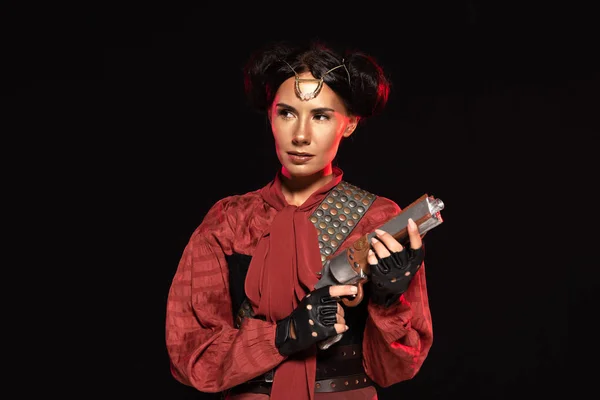 Confident steampunk young woman holding pistol isolated on black — Stock Photo