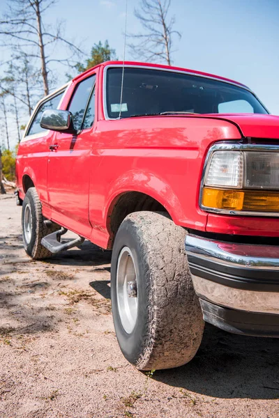 Red car with dirty wheels on ground in forest in sunny day — Stock Photo