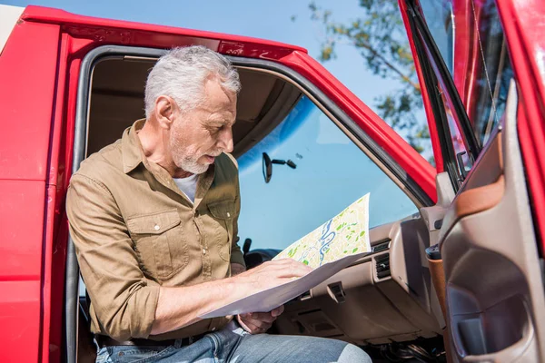 Viajero senior sentado en coche y sosteniendo el mapa en un día soleado - foto de stock