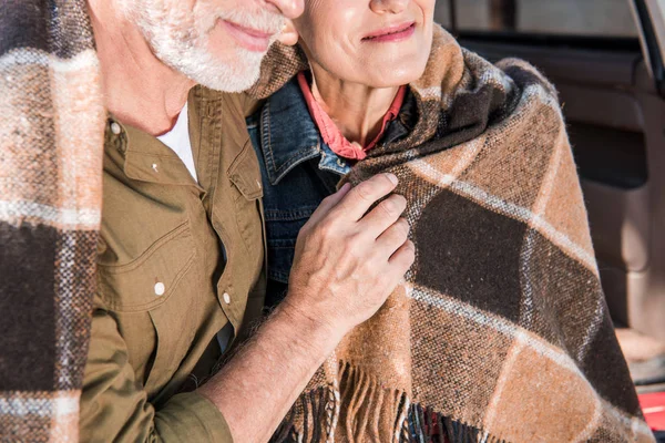 Cropped view of senior couple sitting in car with blanket — Stock Photo