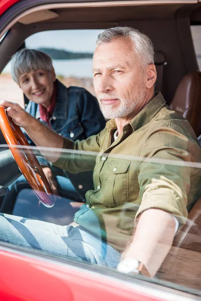 Пожилая пара, сидящая в машине в солнечный день — стоковое фото