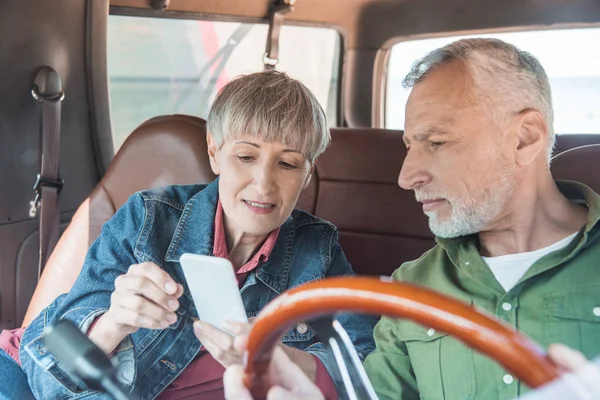 Seniorenpaar nutzt Smartphone im Auto bei sonnigem Tag — Stockfoto
