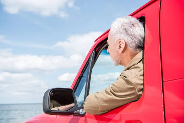 Homem sênior olhando para o rio de carro vermelho — Fotografia de Stock