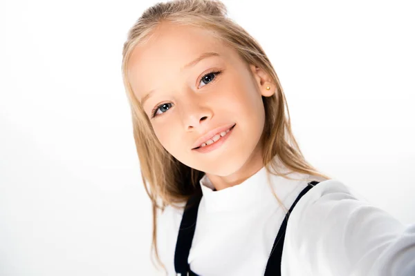 Joyeuse écolière souriant à la caméra tout en prenant selfie sur fond blanc — Photo de stock