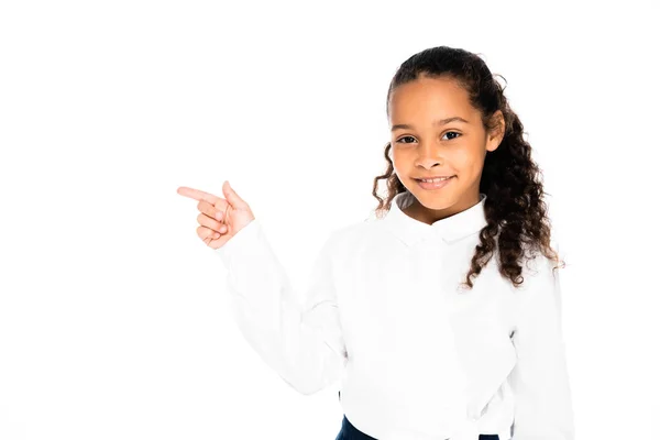 Adorable african american schoolgirl pointing with finger while looking at camera isolated on white — Stock Photo