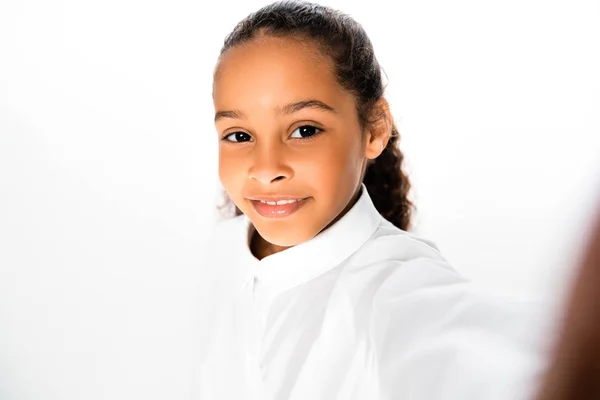 Вибірковий фокус усміхненої афроамериканської школярки, яка дивиться на камеру на білому тлі — стокове фото