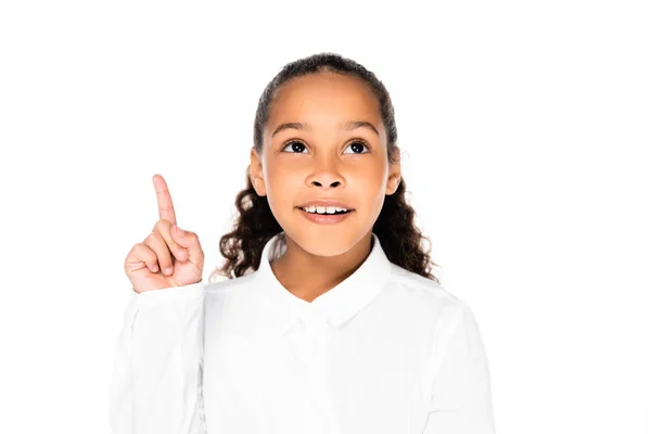 Cheerful african american schoolgirl looking up and showing idea gesture isolated on white — Stock Photo