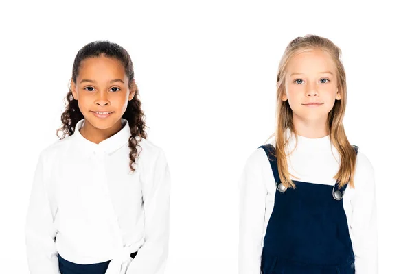 Duas adoráveis alunas multiculturais sorrindo para a câmera isolada em branco — Fotografia de Stock