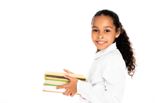 Entzückende afrikanisch-amerikanische Schulmädchen lächelt in die Kamera, während sie Bücher isoliert auf weiß hält — Stockfoto