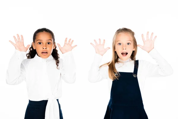 Dos colegialas multiculturales sorprendidas mostrando las manos manchadas de tiza aisladas en blanco - foto de stock