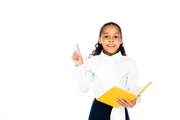 Fröhliche afrikanisch-amerikanische Schülerin hält Buch und zeigt Idee Geste isoliert auf weiß — Stockfoto