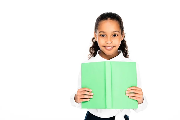 Alegre africano americano colegiala sonriendo a cámara mientras celebración libro aislado en blanco - foto de stock