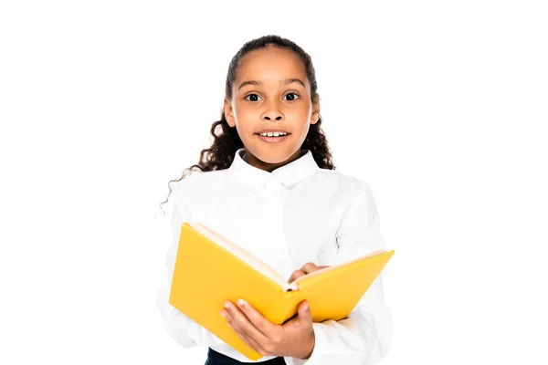 Aufgeregtes afrikanisch-amerikanisches Schulmädchen hält Buch in der Hand und blickt isoliert auf weiße Kamera — Stockfoto