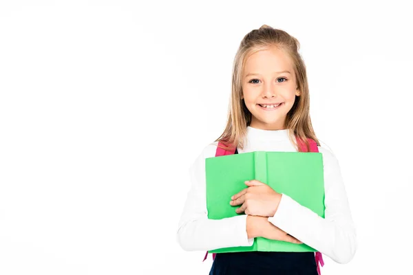Entzückendes, fröhliches Schulmädchen, das Buch in der Hand hält und in die Kamera lächelt, isoliert auf weiß — Stockfoto