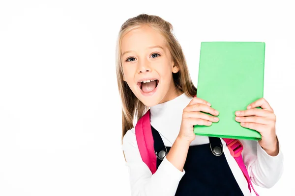 Fröhliches Schulmädchen, das in die Kamera blickt, während es Buch isoliert auf Weiß hält — Stockfoto