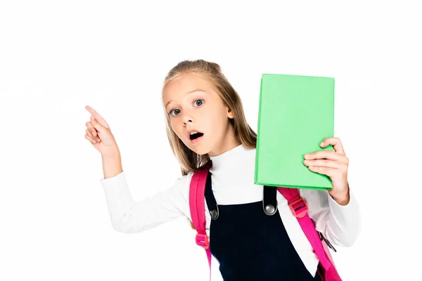 Überraschte Schülerin zeigt mit dem Finger, während sie Buch in der Hand hält und isoliert auf weiße Kamera schaut — Stockfoto