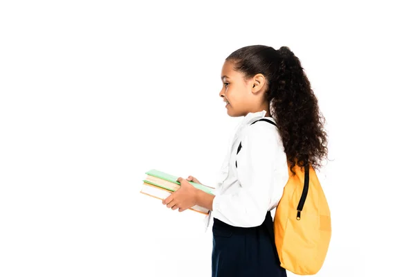 Вид збоку афроамериканської школярки з рюкзаком проведення книг, ізольованих на білому — стокове фото