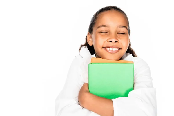 Glückliches afrikanisch-amerikanisches Schulmädchen lächelt mit geschlossenen Augen, während sie Bücher isoliert auf weiß hält — Stockfoto