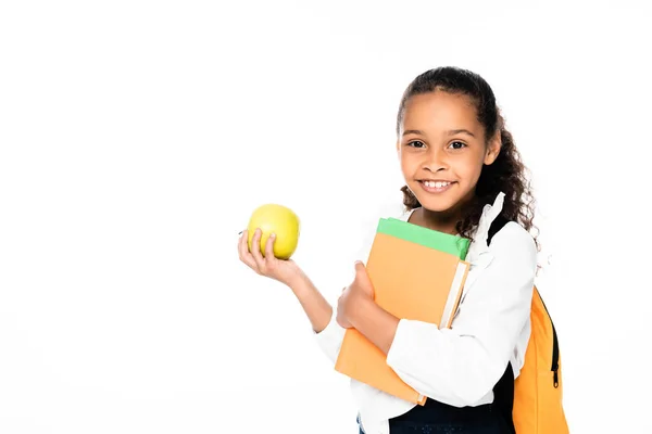 Lächelnde afrikanisch-amerikanische Schülerin hält Bücher und Apfel isoliert auf weiß — Stockfoto
